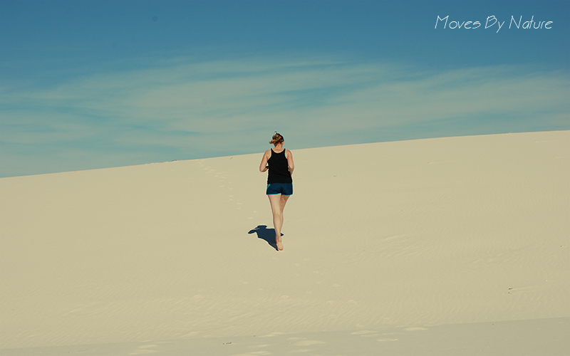 Woman running on a white sand dune