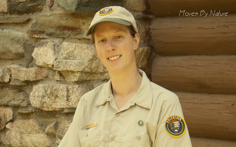 A woman in volunteer ranger outfit in front of a wall