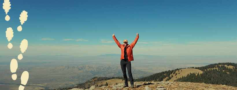 woman cheering on top of a mountain